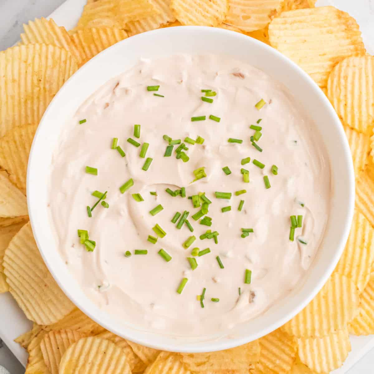 square image of 1 minute french onion dip topped with chives, bowl surrounded by potato chips