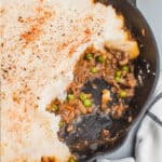 square image of 20-minute shepherd's pie in a cast iron skillet with a portion taken out to show the filling