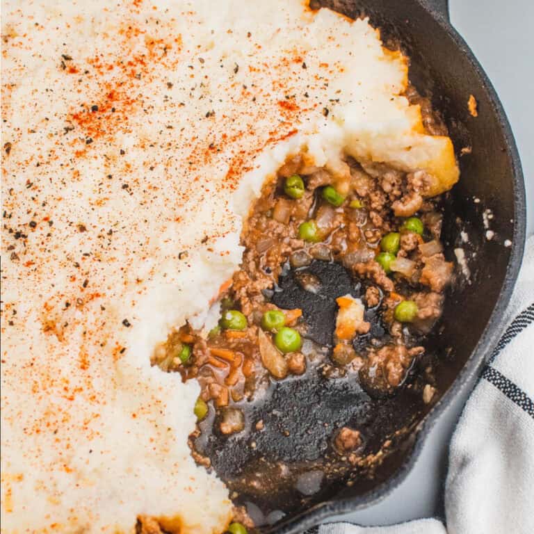 square image of 20-minute shepherd's pie in a cast iron skillet with a portion taken out to show the filling