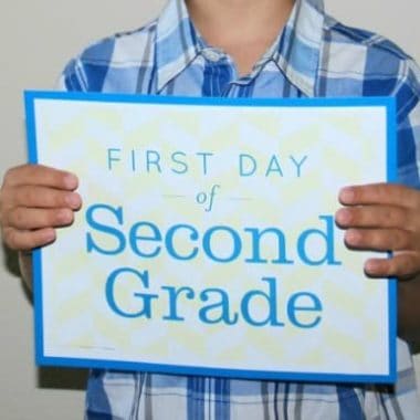 child holding a first day of second grade sign