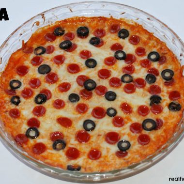 pizza dip in a clear bowl topped with olives and pepperoni