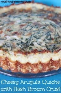 cheesy arugula quiche with has brown crust on a plate