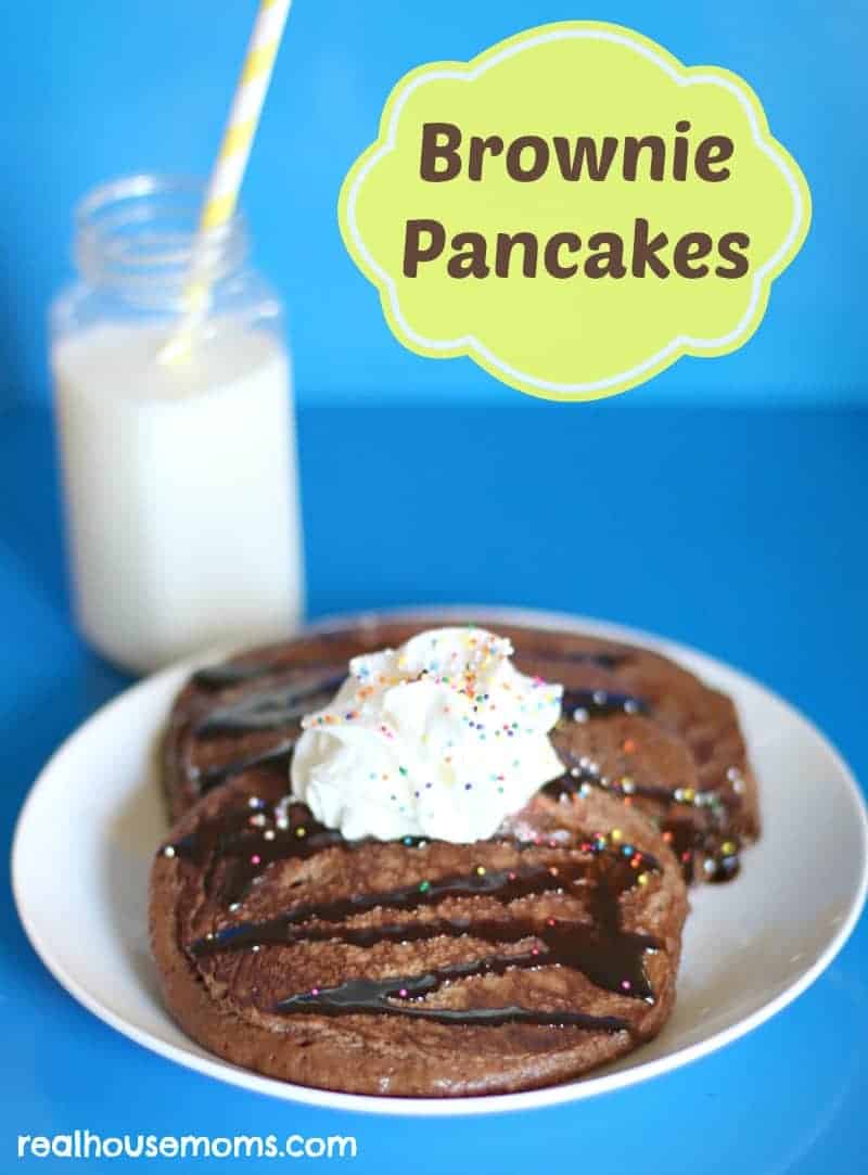 brownie pancakes topped with whipped cream on a plate and a glass of milk