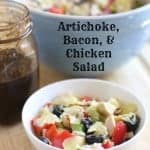 artichoke, bacon & chicken salad in a white bowl with dressing in mason jar