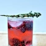 thyme berry sparkler drink in a glass topped with thyme