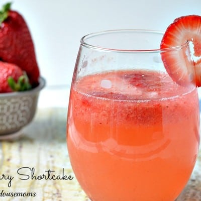 spiked strawberry shortcake drink in a glass with strawberry garnish