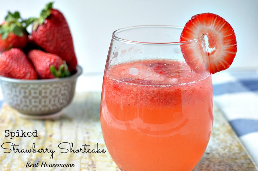 spiked strawberry shortcake drink in a glass with strawberry garnish