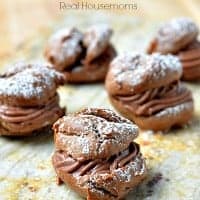 chocolate cream puffs topped with powdered sugar on a platter