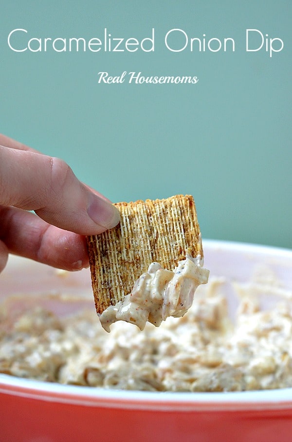hand scooping caramelized onion dip with a cracker