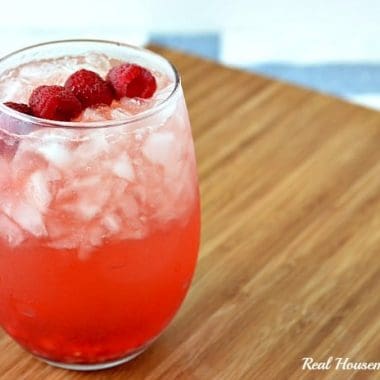 spiked raspberry mango strawberry lemonade in a glass with raspberry garnish