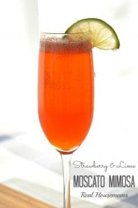 strawberry and lime moscato mimosa in a fluted glass with lime garnish