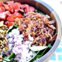 Spinach Bacon and Strawberry Salad displayed in a wooden sharing bowl