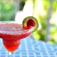 Blended Raspberry Margarita in Margarita glass garnished with Lime slice and resberry