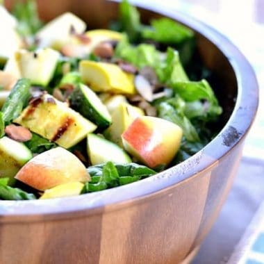 Summer Bounty Salad topped with sliced apples served in a wooden bowl