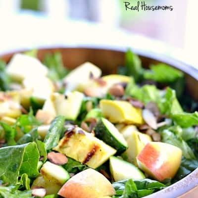 Summer Bounty Salad topped with sliced apples served in a wooden bowl
