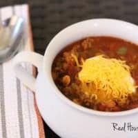 Easy weeknight chili feature displayed in a white sharing dish topped with sour cream and shreaded cheese