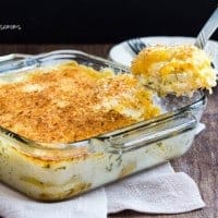 Baking dish with scalloped potatoes and a serving spoon taking a scoop