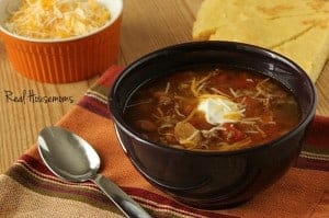 Slow Cooker Three Bean Chili displayed with a side of shreaded cheese