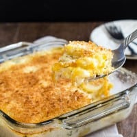 Baking dish with scalloped potatoes and a serving spoon taking a scoop