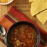 Slow Cooker Three Bean Chili displayed with a side of shreaded cheese
