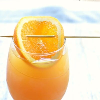 Caramel Hard Apple Cider garnished with a orange slice served in a stimless white wine glass