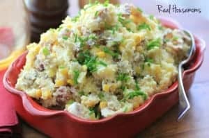 Warm Bacon Corn Smashed Potato Salad served in red baking dish