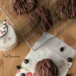 Double Chocolate Covered Cherry Cookies displayed on a baking rack two off to the side on a napkin with a side of milk