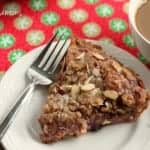 Easy Cranberry Almond Cream Cheese Coffee Cake, close up of slice of cake on a white serving dish with a side of coffee