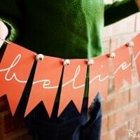 Printable believe banner, child holding banner, Banner is red with red and white string with bells at the top