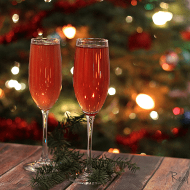 Cranberry Champagne Cocktail, cranberry and elderberry cocktail served in two champaign flutes christmas tree in the background