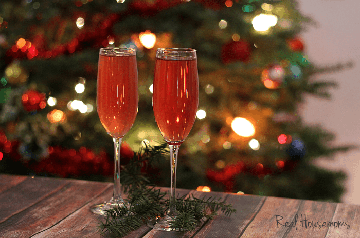Cranberry Champagne Cocktail, cranberry and elderberry cocktail served in two champaign flutes christmas tree in the background