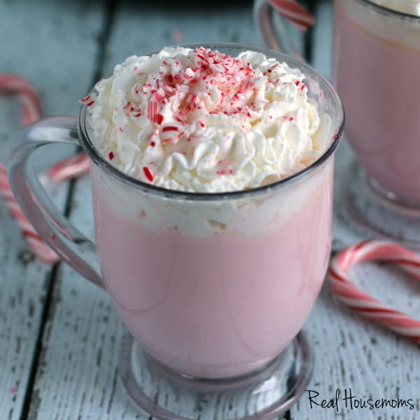 Slow Cooker Candy Cane White Hot Chocolate Candy Cane Hot Cocoa topped with whipped cream and garnished with a candy cane served in a glass mug
