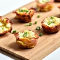 Ham Swiss and Egg cups topped with chives served on a cutting board
