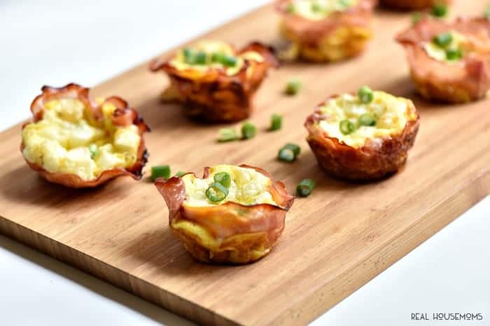 Ham Swiss and Egg cups topped with chives served on a cutting board