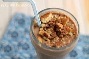close up of Skinny Tiramisu Smoothie. served in a smoothie glass with a white and blue straw