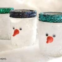Snowman Mason Jars. Mason jars covered in fake snow tops painted in glitter. Orange cran tip for the snowman's nose
