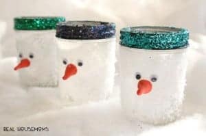 Snowman Mason Jars. Mason jars covered in fake snow tops painted in glitter. Orange cran tip for the snowman's nose