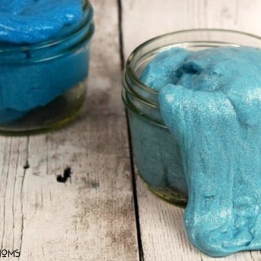 Homemade glitter putty. Two mason jars of blue silly putty on a wood table