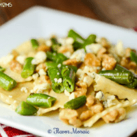 Ravioli Gorgonzola with Walnuts and Green Beans. Served on a white dish.