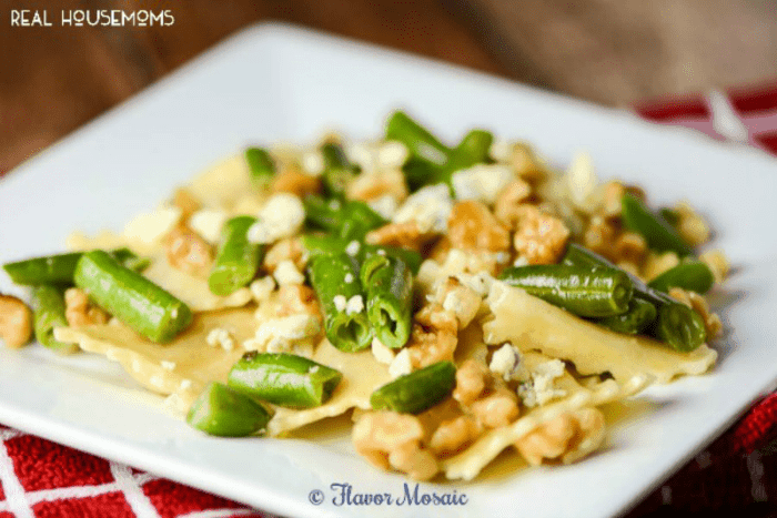 Ravioli Gorgonzola with Walnuts and Green Beans. Served on a white dish.
