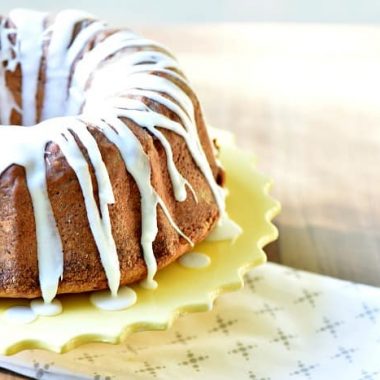 Lemon Pound Cake. Drizzled with white frosting displayed on a round yellow vake stand