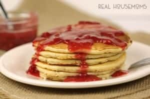 Pancakes with Easy Raspberry Sauce. Sick Pancakes stacked served on a large white plate.