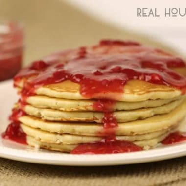 Pancakes with Easy Raspberry Sauce. Sick Pancakes stacked served on a large white plate.