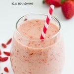 Tropical Strawberry Smoothie. served in a stemless whine glass garnish and served with strawberries.