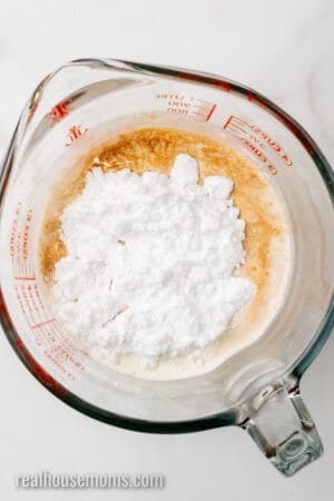 heavy cream, vanilla extract, and powdered sugar replacement in a glass measuring cup
