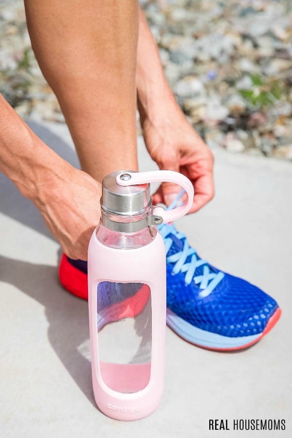 woman tying running show with a water bottle next to her