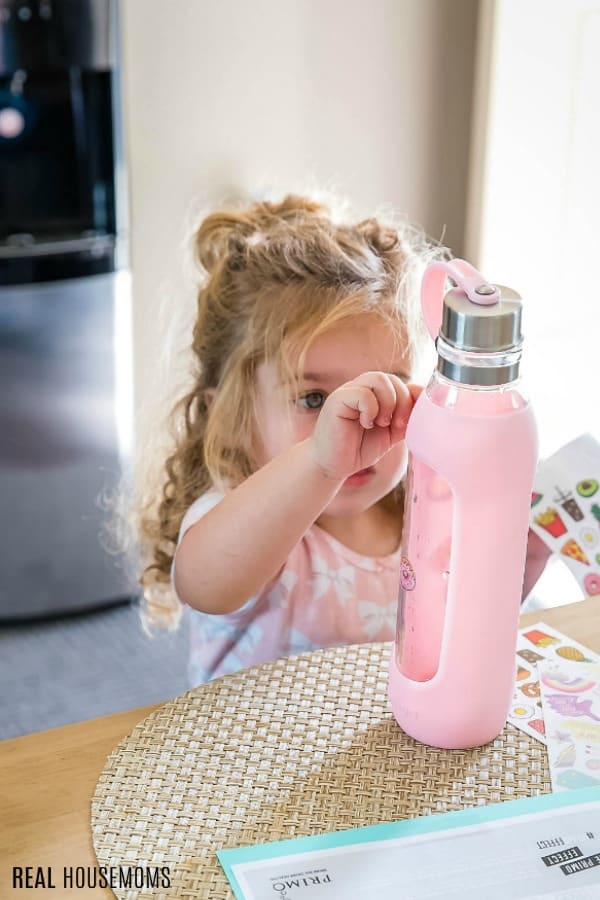 little girl putting stickers on a reusable water bottle