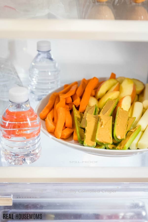 water bottles next to a plate of healthy snacks in the fridge