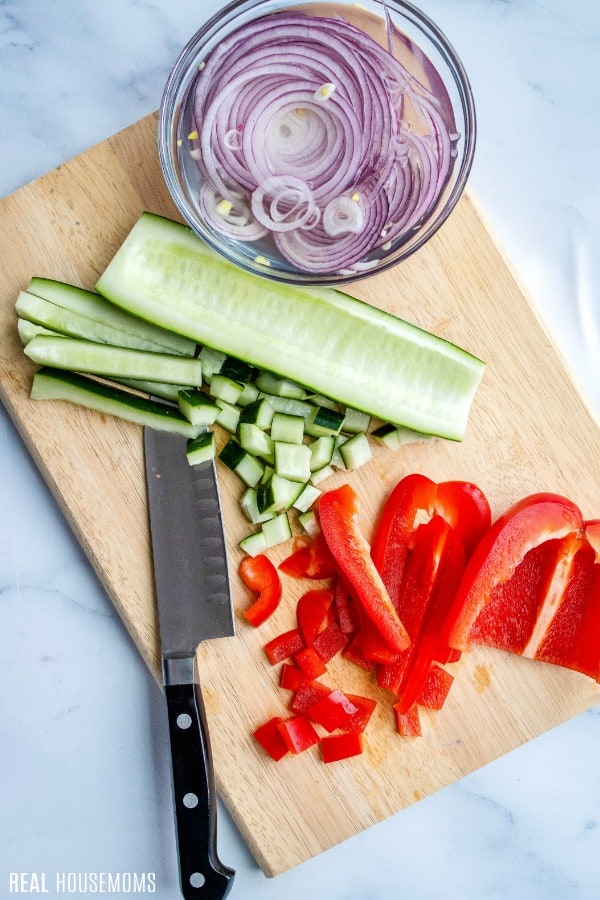 veggies for 7 layer salad being chopped on a cutting board