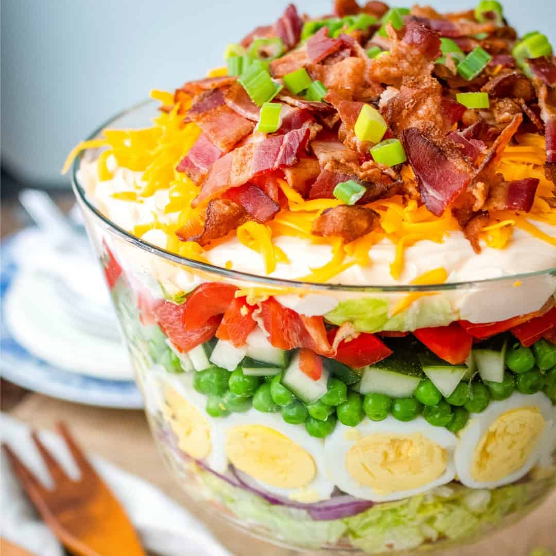 Classic 7 Layer Salad is an easy, make-ahead recipe perfect for a crowd! With crisp veggies and tangy dressing layered on top, it's a potluck favorite!